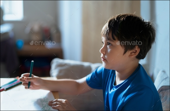 kid using green pen drawing on paper, Cute Child boy colouring and watching TV in living room