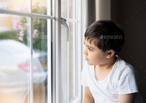 Kid looking at the midge climbing up outside of double glazed window. Young boy looking at insect