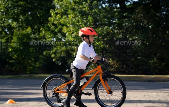 School kid learns to ride a bike in the Park,Child boy in helmet riding a bicycle on the road