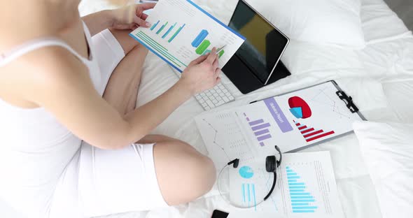 A Businesswoman on the Bed Holds a Statistical Report