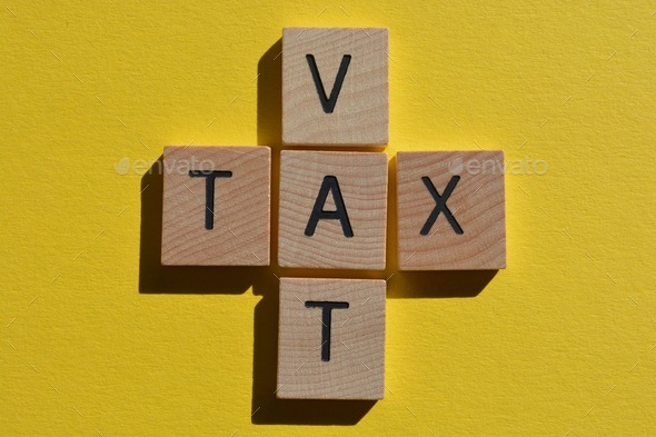 Word tax and acronym VAT Value Added Tax, in 3D wooden alphabet letters in crossword form.