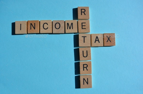 Income Tax Return words in 3D wooden letters in crossword form on s