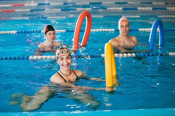 Group of happy people on aqua fitness in swimming pool.