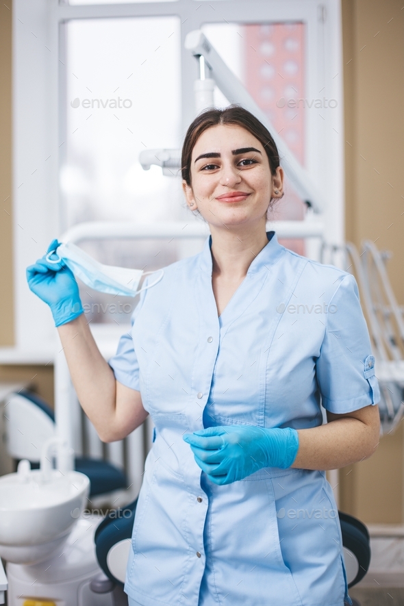 Eastern woman in medical robe pose to camera in dentist office. Stock Photo by olesyaklyots