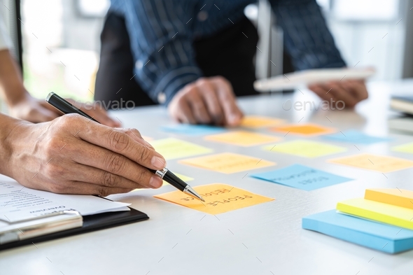 Two creative business people meeting and planning use post it notes sticky note on desk to share