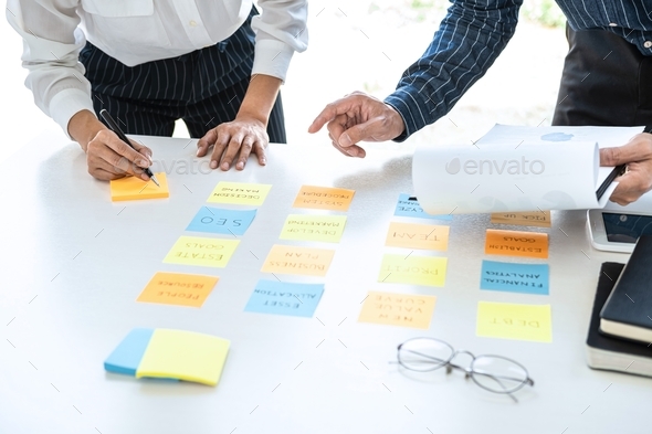 Two creative business people meeting and planning use post it notes sticky note on desk to share