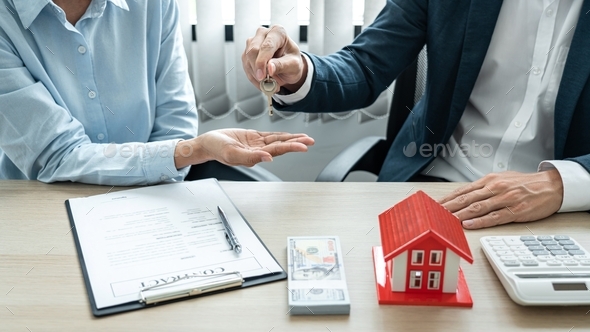 Real estate broker agent holding filing keys to the customer after signing rental lease contract