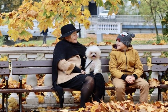 Grandma with grandson and a furry friend sitting on a bench in the park.