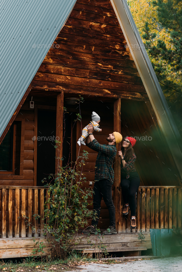 A happy young couple with a child at the cottage - Stock Photo - Images