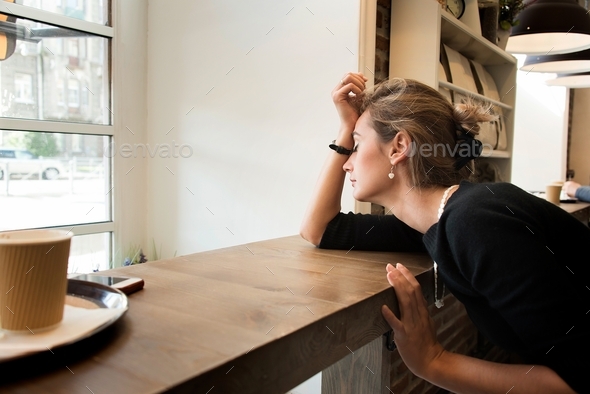 ↟ Beautiful young woman in a cafe is bored alone