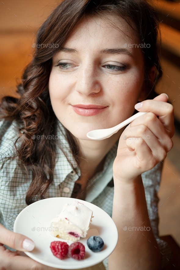 Beautiful girl alone in a cafe. A girl in a cafe eats a cake Stock