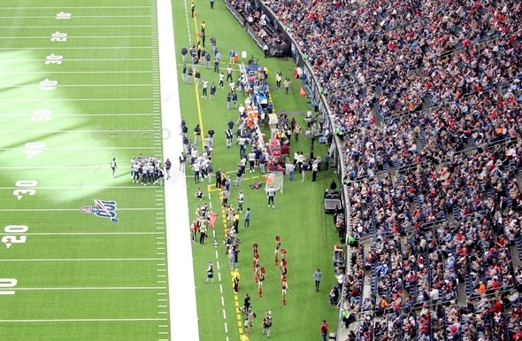 An audience of sports fans watching an NFL football game in a stadium - Stock Photo - Images
