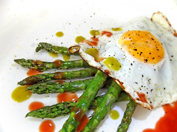 Brunch food - fried egg on grilled asparagus with spicy habanero & jalapeno sauces