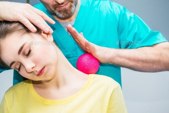 Woman at the physiotherapy receiving ball massage from a therapist. A chiropractor treats patient\'