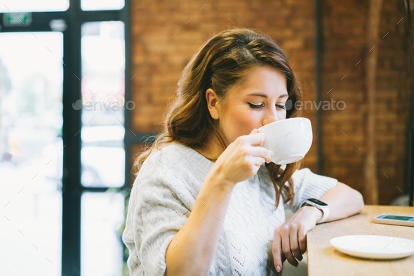 Young Woman drinking coffee during the break or lunch time in the cafe. Time to relax