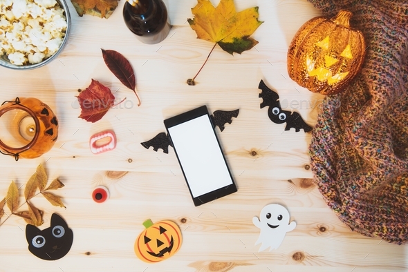 smart phone with blank screen decorated with bat wings and traditional Halloween decor - bats, ghost