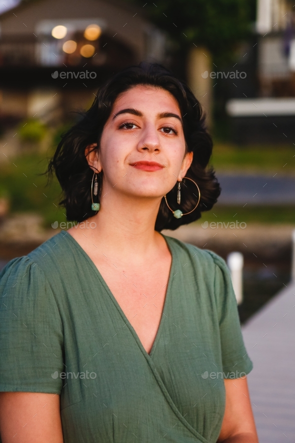 Beautiful Latina biracial Hispanic young woman with hoop earrings on a dock during golden hour