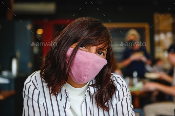Hispanic Latina woman wearing a face mask at a restaurant and looking at the camera