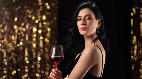 Portrait of Fashion Woman with Glass of Red Wine Posing at Disco Party alt