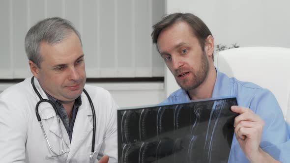 Two Mature Male Doctors Discussing MRI Scan of the Patient