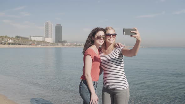 Young adult females photographing self on beach