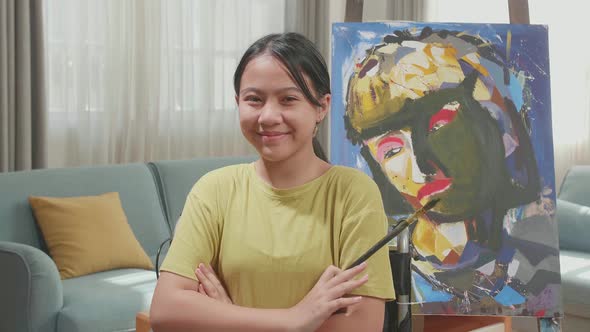 Asian Artist Girl In Wheelchair Holding Paintbrush And Cross His Arms And Smile While Painting alt