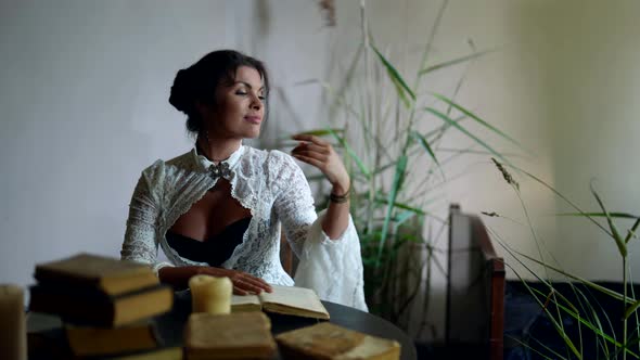 Charming Brunette Woman is Reading Books in Room with Romantic and Historical Atmosphere alt