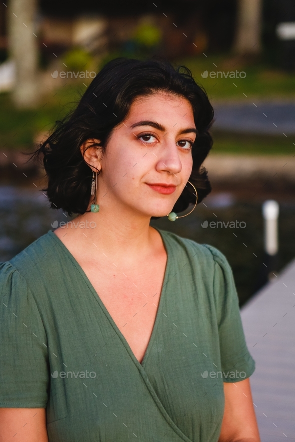 Beautiful confident Latina biracial Hispanic woman with hoop earrings on a dock during golden hour