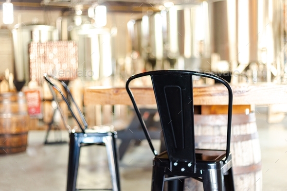 Black metal stools at a brewery with a high table on a barrel - Stock Photo - Images