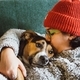 Young woman in an orange beanie and comfy sweater snuggling a comfy dog on the couch - PhotoDune Item for Sale
