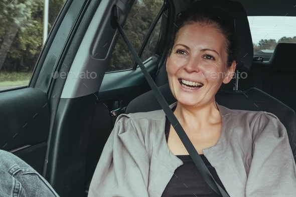 Woman enjoys landscape through car window. passenger use seat belt. Safety driving traveling concept