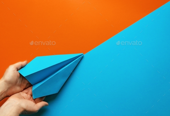 Blue paper plane supported by female hands on colorful background. New beginning, startup, support