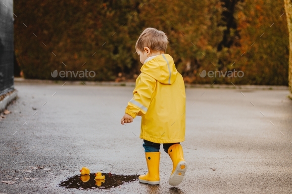 Little toddler child playing with toys outdoors after rain