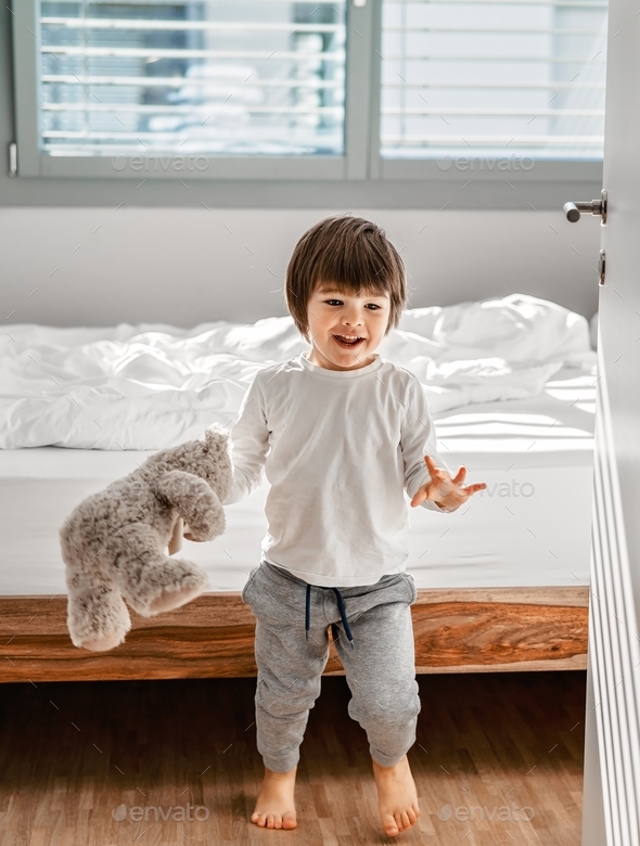 Cute little happy barefoot child playing with soft teddy bear toy in ...