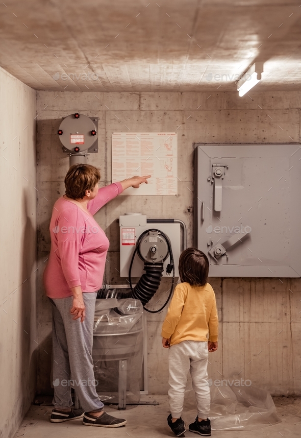 Senior woman with little child reading rules and instruction in nuclear fallout shelter