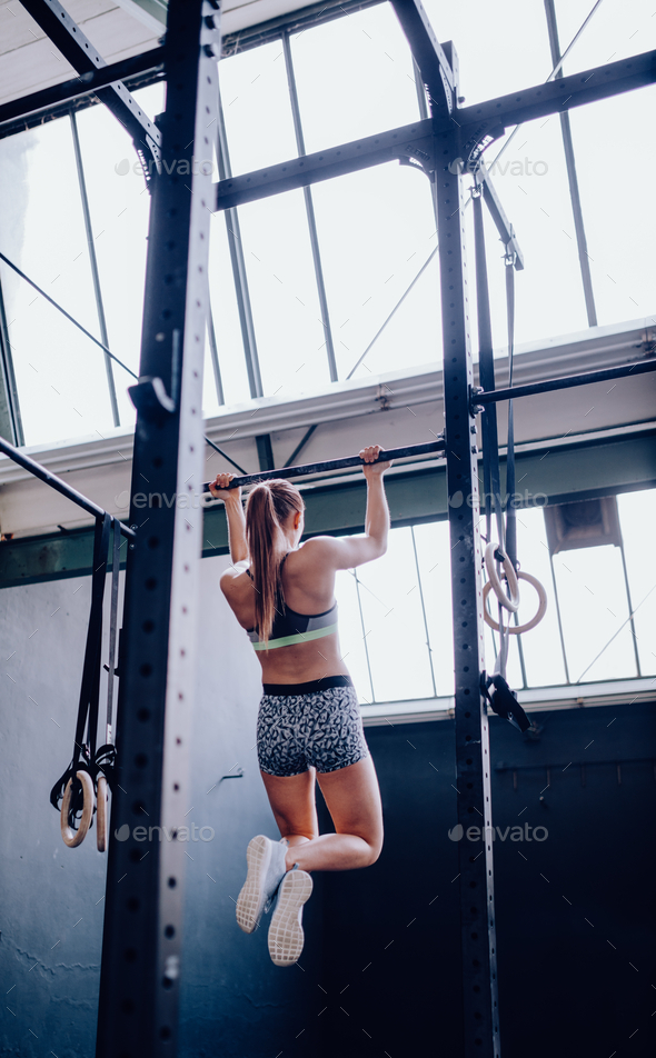 Strong girl doing pull-up on bar in gym Stock Photo by crieneimages