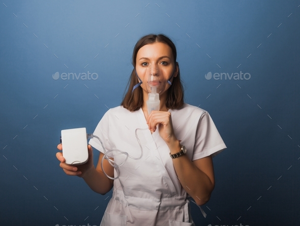 woman makes an inhalation nebulizer. holding a mask by a nebulizer inhaling vapors. self-medication