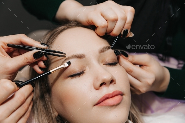 girl makes eyebrow styling in a beauty salon. the master combs his eyebrows. eyelash extensions