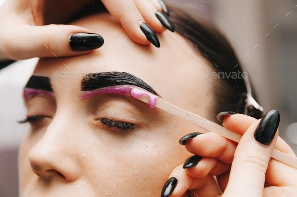 the master applies wax on the eyebrows to remove excess hairs. eyebrow care.
