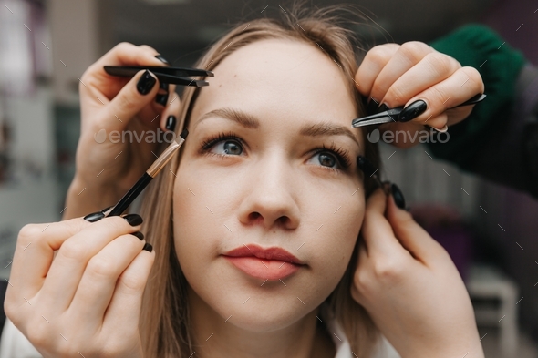 girl makes eyebrow styling in a beauty salon. the master combs his eyebrows. eyelash extensions