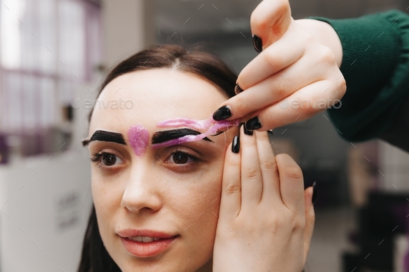 eyebrow waxing. the master makes hair removal with wax.removal of excess hairs on the eyebrows
