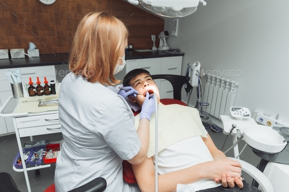 Drilling teeth and sucking saliva with an ejector. dentist treats ...