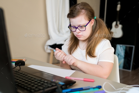 teenager girl with Down syndrome learning online at home. Distance ...