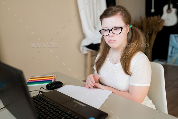 teenager girl with Down syndrome learning online at home. Distance ...