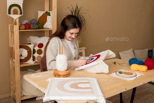  Female embroidering handmade picture rainbow on canvas.