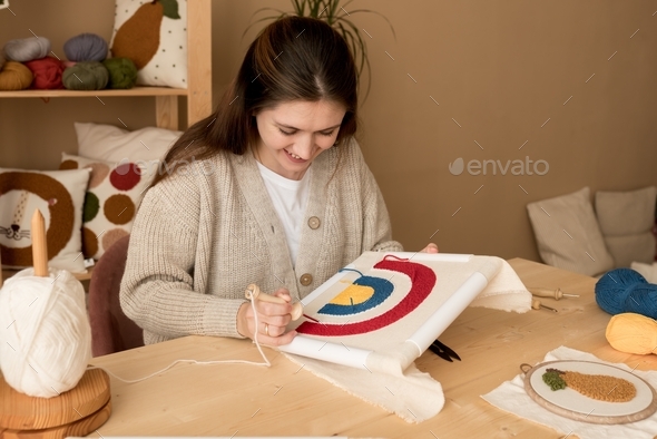  Female embroidering handmade picture rainbow on canvas.