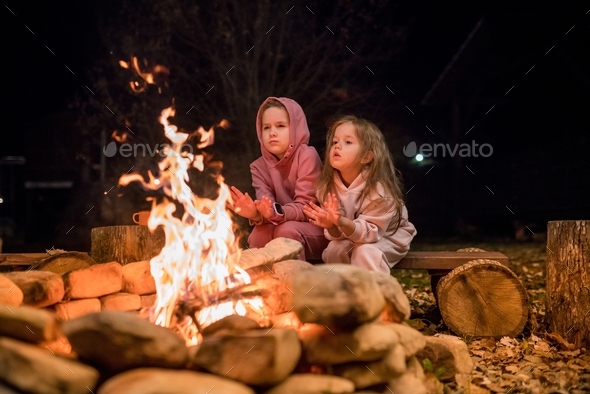 Girls warming their hands by the bonfire.