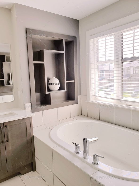 White tiles around bathtub, decorative shelving in bathroom, modern interior design, new home