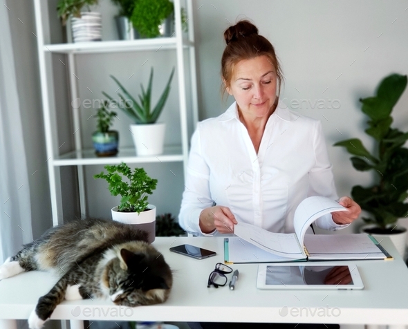 Business woman checks her agenda for the day, working from home with her cat nearby