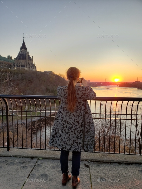 Traveling Woman is cought in the moment of capturing beauty of sunset